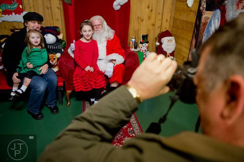 Jon Moran (right) takes a photo of his daughters Sabrina and Charlotte and his wife Kristen as they visit with Santa Claus at Ronald and Betty Page's home in Canton on Thursday, December 12, 2013. 