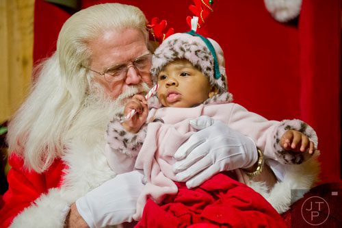 Santa Claus (left) visits with Faith Bailey as she plays with a candy cane at Ronald and Betty Page's home in Canton on Thursday, December 12, 2013.