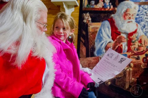 Santa Claus (left) visits with Emily Jackson as she shares her Christmas list at Ronald and Betty Page's home in Canton on Thursday, December 12, 2013. 