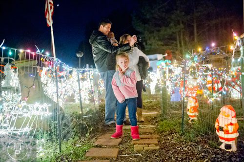 Evie Silva (front) walks through the lights at Ronald and Betty Page's home in Canton with her father Enzo, brother Elias and mother Paige on Thursday, December 12, 2013.
