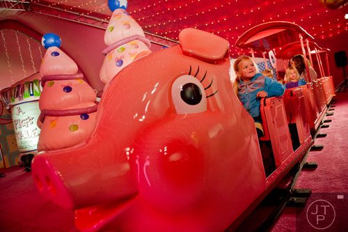 Hadley Young (left) rides the Macy's Pink Pig at Lenox Square Mall in the Buckhead neighborhood of Atlanta on Tuesday, November 26, 2013. 