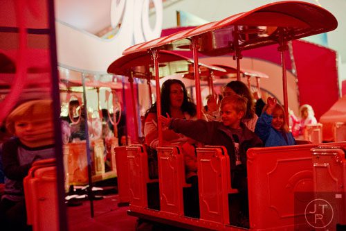 Dallas Woody (left) and Emily Brooks ride the Macy's Pink Pig at Lenox Square Mall in the Buckhead neighborhood of Atlanta on Tuesday, November 26, 2013. 