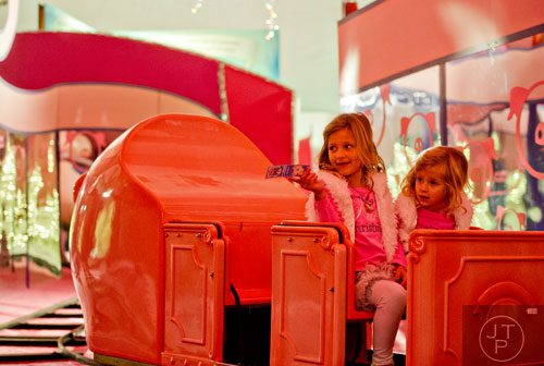 Bailey Petronis (left) and her sister Olivia ride the Macy's Pink Pig at Lenox Square Mall in the Buckhead neighborhood of Atlanta on Tuesday, November 26, 2013. 