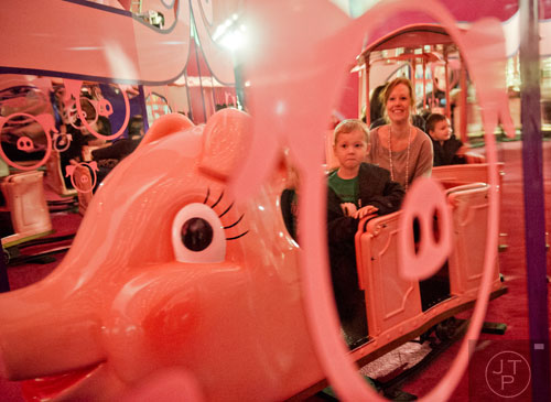 Charles Griffin (left) and his mother Nicole ride the Macy's Pink Pig at Lenox Square Mall in the Buckhead neighborhood of Atlanta on Tuesday, November 26, 2013. 