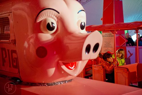 Virginia Fisher (left) and Jordan Webster ride the Macy's Pink Pig at Lenox Square Mall in the Buckhead neighborhood of Atlanta on Tuesday, November 26, 2013.