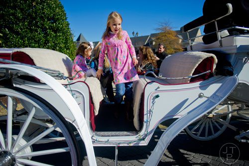 Catherine Cullinan (center) climbs onto a horse drawn carriage past her sister Lia at the The Forum in Peachtree Corners on Friday, November 29, 2013. 