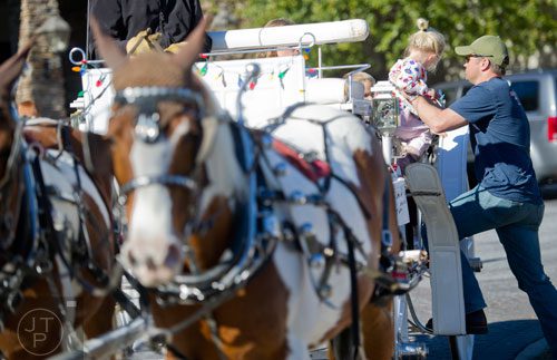 Ted Boezaart (right) lifts his daughter Zani onto a horse drawn carriage at the The Forum in Peachtree Corners on Friday, November 29, 2013.
