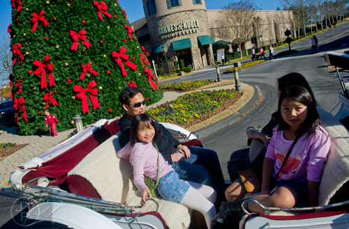 Kimberly Pham (left), her father Ken, mother Van and sister Kayla ride a horse drawn carriage around the The Forum in Peachtree Corners on Friday, November 29, 2013. 
