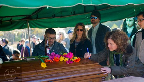 Gigi Gits (right) signs the casket of Ria Pell at the Westview Cemetery in Atlanta on Saturday, November 30, 2013. 