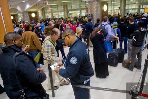 Michael Lee (center) checks a passenger's ticket while working the security line at Hartsfield-Jackson International Airport in Atlanta on Sunday, December 1, 2013.