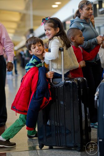 Matthew Praxedes (left) pushes his sister Carolline as she rides on a suitcase at Hartsfield-Jackson International Airport in Atlanta on Sunday, December 1, 2013.  