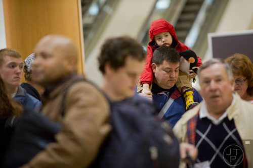 Ethan Pollack (right) sits on his father Ari's shoulders as they wait in the security line at Hartsfield-Jackson International Airport in Atlanta on Sunday, December 1, 2013.   