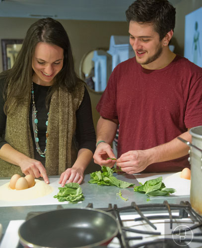 Danielle Zamarelli (left) and Chris Akavi pick basil leaves as they prepare handmade ravioli during the Pastabilities class at The Cooking School at Irwin Street in Atlanta on Saturday, January 18, 2014.    