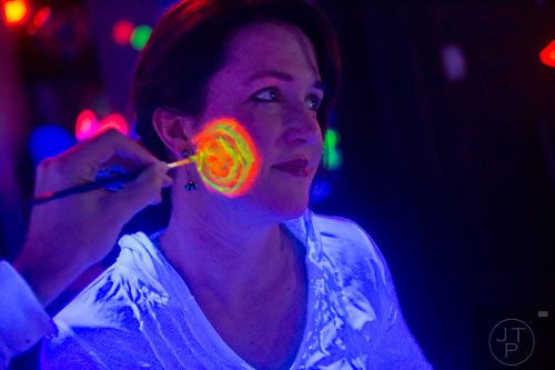 Alex Wright has her face painted by her husband Dave during "Black Light Art" Adult Saturday Night at Zone of Light Studio in Atlanta on Saturday, January 18, 2014. 