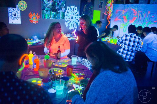 Ashley Bryant (left) laughs with Amy Wilson during "Black Light Art" Adult Saturday Night at Zone of Light Studio in Atlanta on Saturday, January 18, 2014. 