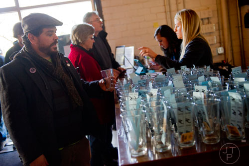 Scott Hutchison (left) grabs his glass and tasting tickets as he enters the Great Southern Craft Beer Competition Kickoff Party at Monday Night Brewing in Atlanta on Sunday, January 19, 2014. 