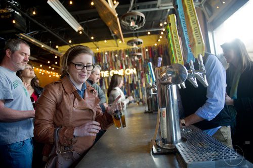 Marti Williamson (center) grabs her glass of beer to taste during the Great Southern Craft Beer Competition Kickoff Party at Monday Night Brewing in Atlanta on Sunday, January 19, 2014. 