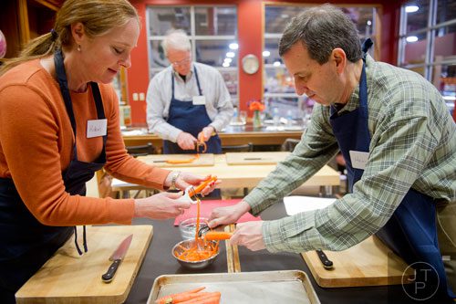 Robin Heim (left), her husband Skip and Henry Abelman (right) peel carrots during a cooking class at the Salud Cooking School at Harry's Farmers Market in Roswell on Thursday, January 23, 2014.