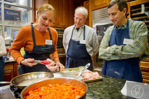 Robin Heim (left) places chicken quarters in a pan as her husband Skip and Henry Abelman watch during a cooking class at the Salud Cooking School at Harry's Farmers Market in Roswell on Thursday, January 23, 2014. 
