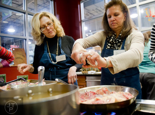 Becky Sorenson (right) seasons chicken quarters in a pan as Jan Wright watches during a cooking class at the Salud Cooking School at Harry's Farmers Market in Roswell on Thursday, January 23, 2014. 