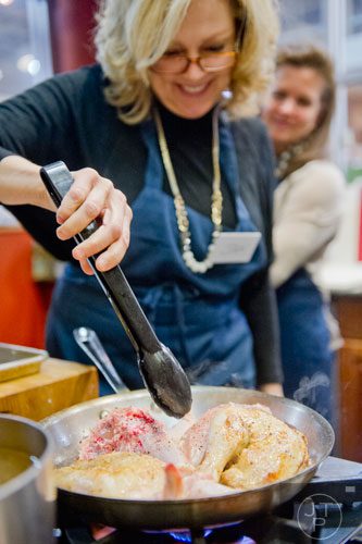 Jan Wright (left) flips chicken quarters in a pan as Becky Sorenson watches during a cooking class at the Salud Cooking School at Harry's Farmers Market in Roswell on Thursday, January 23, 2014. 