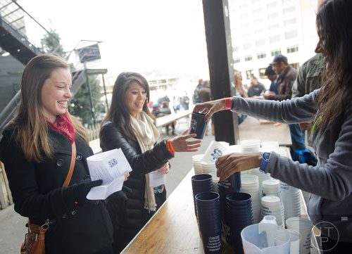 Christine Brumfield (left) and Marissa Seto are handed their tasting glasses by Nelam Patel during the Atlanta Winter Beerfest at the Masquerade in Atlanta on Sunday, January 26, 2014.