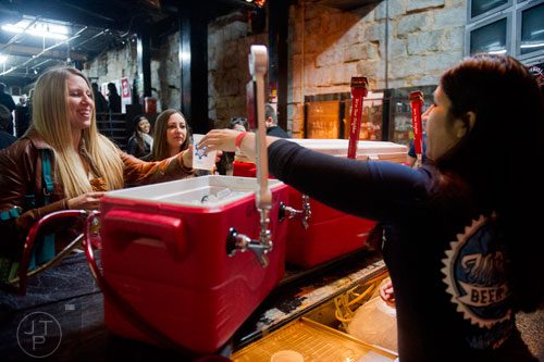 Karen Radakovich (left) is handed a beer by Valerie Mac (right) as she and Kristina Photakis make their way through the Atlanta Winter Beerfest at the Masquerade in Atlanta on Sunday, January 26, 2014. 