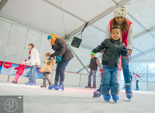 Erin Webb (right) teaches her son Kevin Jr. to ice skate at Centennial Olympic Park in downtown Atlanta on Sunday, December 8, 2013.   