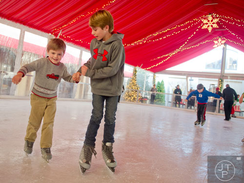 Hayes Lusink (left) learns to ice skate with the help of his brother Bishop at the St. Regis in Buckhead on Wednesday, December 18, 2013. 