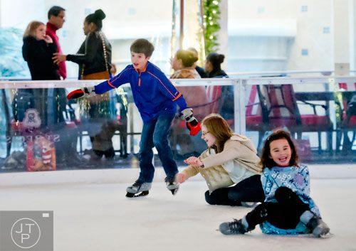 Colin Gibney (left) skates past Anna Cochran and Julia Gibney as they pick themselves up off of the ice at the St. Regis in Buckhead on Wednesday, December 18, 2013. 