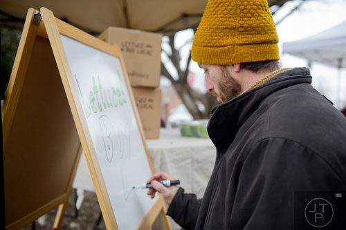 Jonathan Hehn finishes setting up his booth by writing on a sign at the Decatur Farmers Market on Saturday, January 4, 2014.