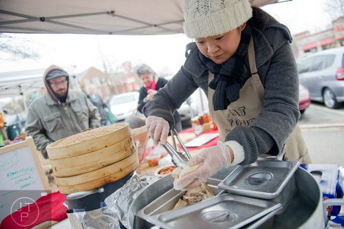 Hannah Chung (right) prepares stuffed steamed buns topped with kimchi at her Simply Seoul booth at the Decatur Farmers Market on Saturday, January 4, 2014.