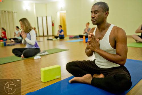 Sandy Rumble (right) concentrates on his breathing during yoga class at Breathe Yoga in Chamblee on Monday, January 6, 2014. 