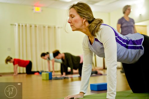 Pam Burnett (right) stretches into a pose during yoga class at Breathe Yoga in Chamblee on Monday, January 6, 2014. 