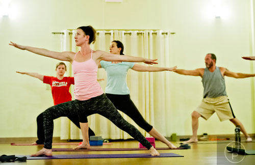 Melissa Dillon (left), Mandy Seaman, Jackie Golden and Greg Isabel stretch into a pose during yoga class at Breathe Yoga in Chamblee on Monday, January 6, 2014. 