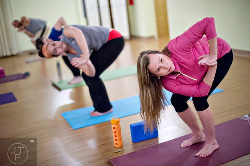 Lauren Loden (right) and Emily Meyer stretch into a pose during yoga class at Breathe Yoga in Chamblee on Monday, January 6, 2014. 