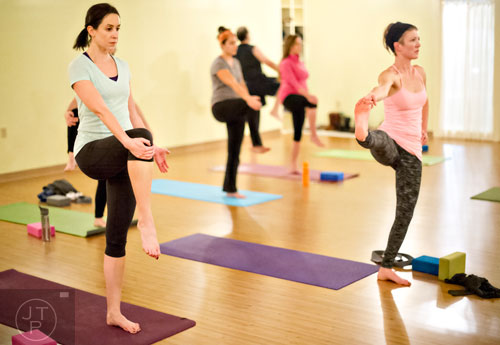 Jackie Golden (left) and Melissa Dillon stretch into a pose during yoga class at Breathe Yoga in Chamblee on Monday, January 6, 2014. 