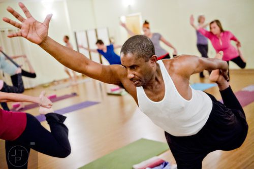 Sandy Rumble (center) stretches into a pose during yoga class at Breathe Yoga in Chamblee on Monday, January 6, 2014. 