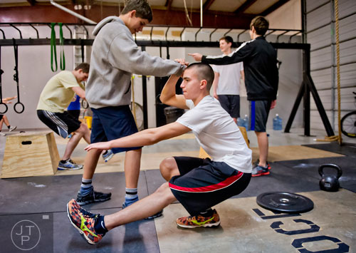 Justin Williams (left) helps Chris Gouin balance as they work out at Operation CrossFit in Alpharetta on Wednesday, January 8, 2014. 