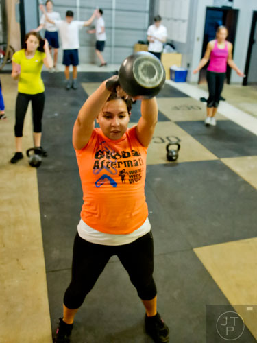 Katherine Perkins (center) lifts a kettlebell as she works out at Operation CrossFit in Alpharetta on Wednesday, January 8, 2014. 