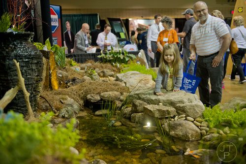 Blayke Ledbetter (center) crawls on a boulder to get a look into the pond on display at the North Atlanta Home Show at the Gwinnett Center in Duluth on Sunday, February 23, 2014. 