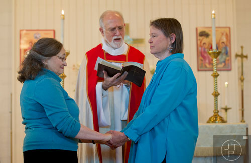Alice Delaney (left) holds her partner MayC Brown's hands during their blessing of the lifelong covenant ceremony led by Rev. Michael A. Tanner (center) at Holy Comforter Church in East Atlanta on Sunday, January 19, 2014.  