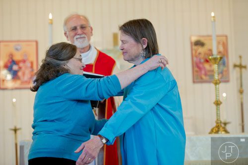 Alice Delaney (left) reaches to hug her partner MayC Brown as Rev. Michael A. Tanner (center) concludes their blessing of the lifelong covenant ceremony at Holy Comforter Church in East Atlanta on Sunday, January 19, 2014.  