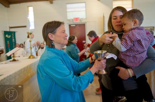 MayC Brown (left) holds up a cup of wine for Dell Giles and her son Milam during communion at Holy Comforter Church in East Atlanta on Sunday, January 19, 2014. 