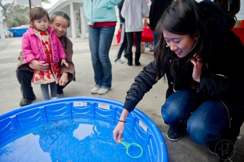 Ashley Wang (right) tries to catch a goldfish as Aliza Snow and her grandmother Gina Lo watch during the Atlanta Chinese Lunar New Year Festival in Chamblee on Saturday, February 1, 2014. 