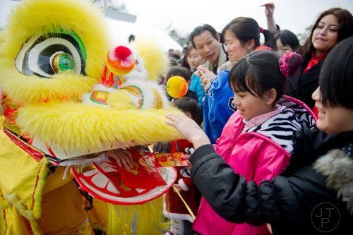 Kaylyn Shao (center) hands an envelope filled with money to one of the Fu dogs that performed during the Atlanta Chinese Lunar New Year Festival in Chamblee on Saturday, February 1, 2014. 