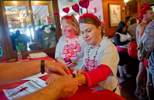 Angie Curtis (center) and Christine Clark receive their wristbands after registering for the Cupid Undies Run at Ri Ra Irish Pub in Midtown on Saturday, February 15, 2014. 