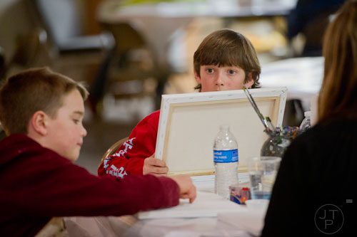 Spencer Fields (center) holds up his canvas as he talks with Stockton Lewis during Mother-Son Date Night at Saville Studios in Peachtree City on Saturday, February 15, 2014. More than 60 sons 