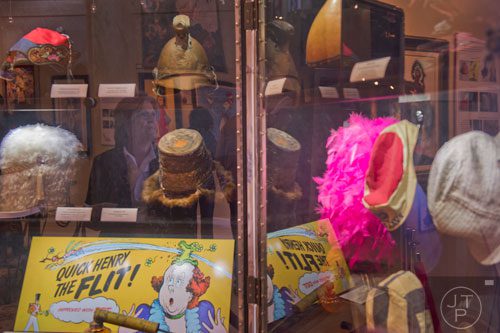 Susan Gruwell (left) is reflected in the glass case containing numerous hats for the "Hats Off to Dr. Seuss" national traveling exhibit at the Ann Jackson Gallery in Roswell on Sunday, February 16, 2014. 