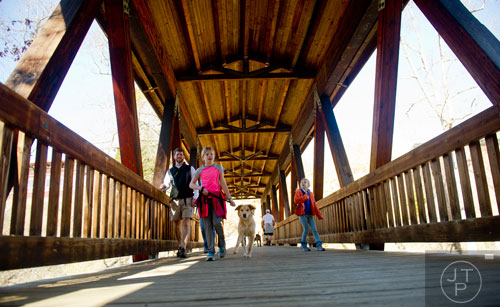 Amelia Shugart (center) walks her dog Willa with her sister Molly and father Ben as they cross the covered bridge at Old Mill Park in Roswell on Sunday, February 16, 2014.